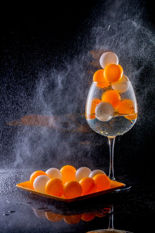 Free A creative still life with orange and white ping pong balls in a glass, surrounded by mist. Stock Photo