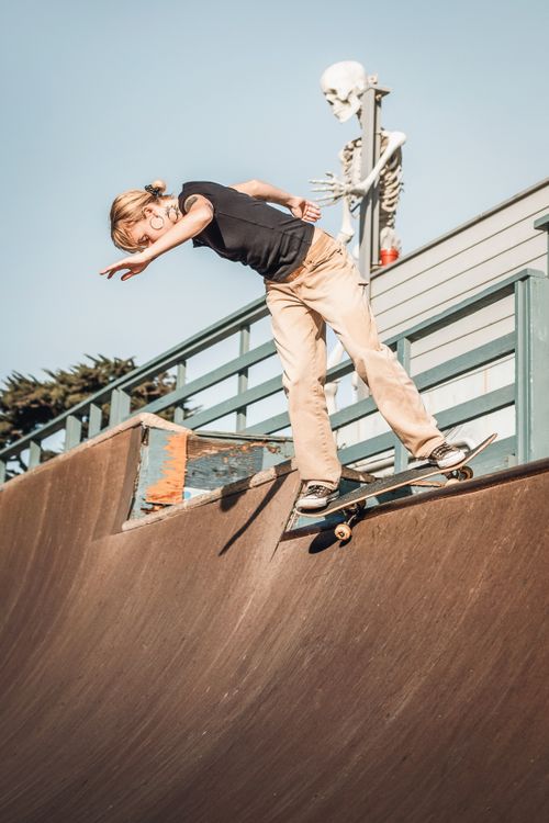 Free A female skater executes a backstall trick at Cayucos Skatepark with a skeleton decor. Stock Photo