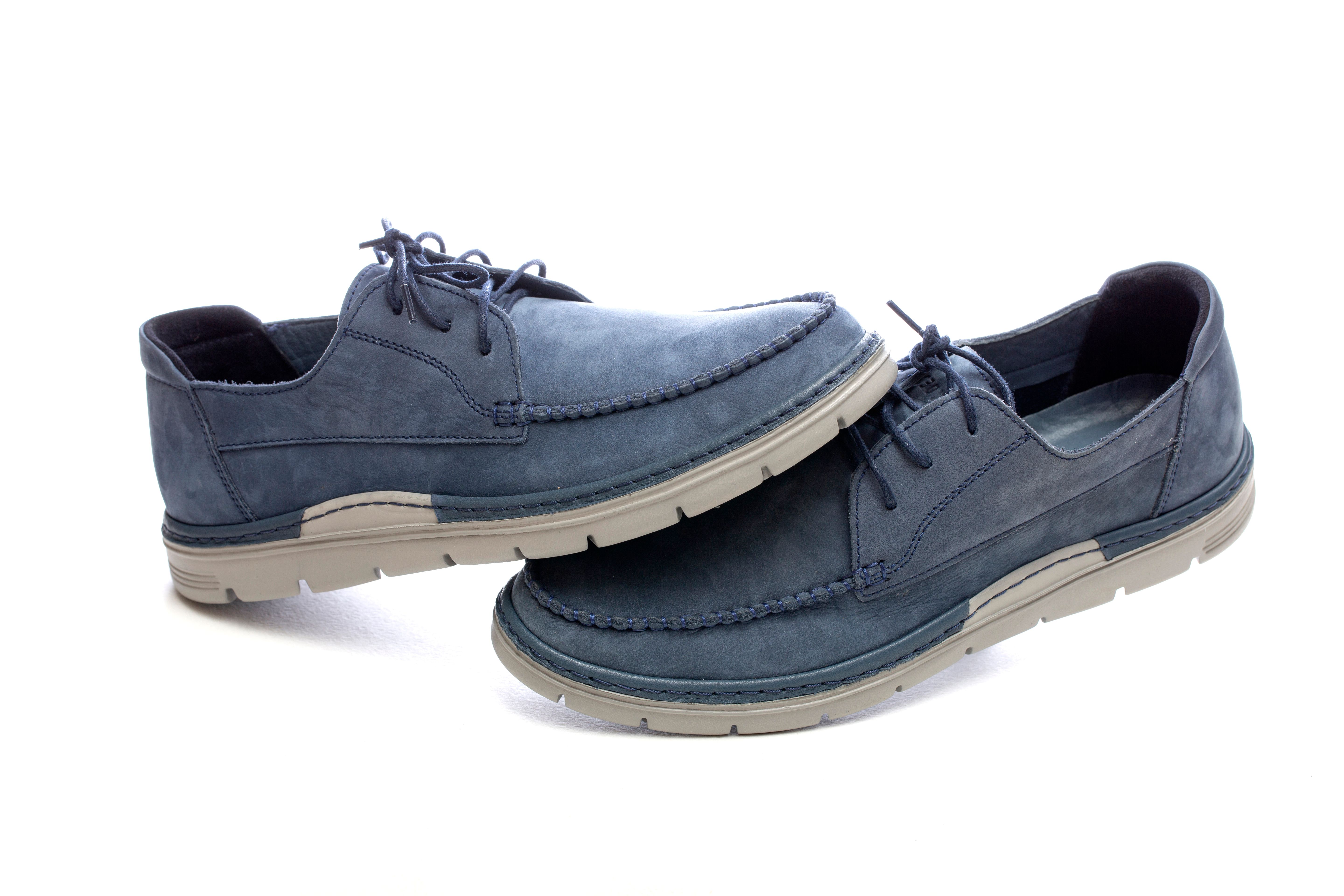 Fotomural Par de mocasines de piel azul con cordones sobre fondo blanco, calzado informal moderno.