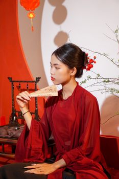 一位身着越南传统服饰的优雅女子，手持扇子，置身于宁静的室内环境中。 - 相关推荐
