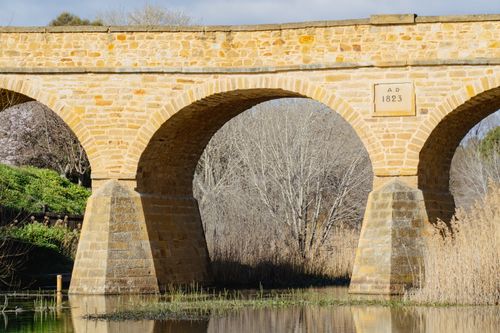 Free Richmond Bridge, built in 1823, reflects in the river below in Tasmania, Australia. Stock Photo