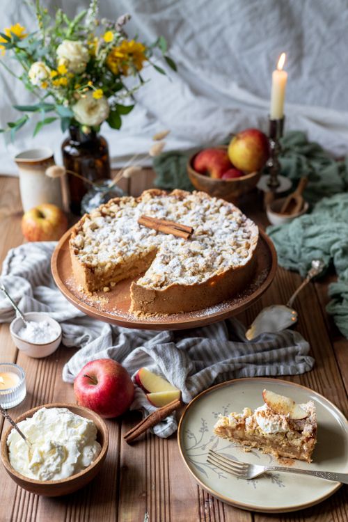 Free Delicious rustic apple pie garnished with cinnamon stick, surrounded by fresh apples and whipped cream. Stock Photo