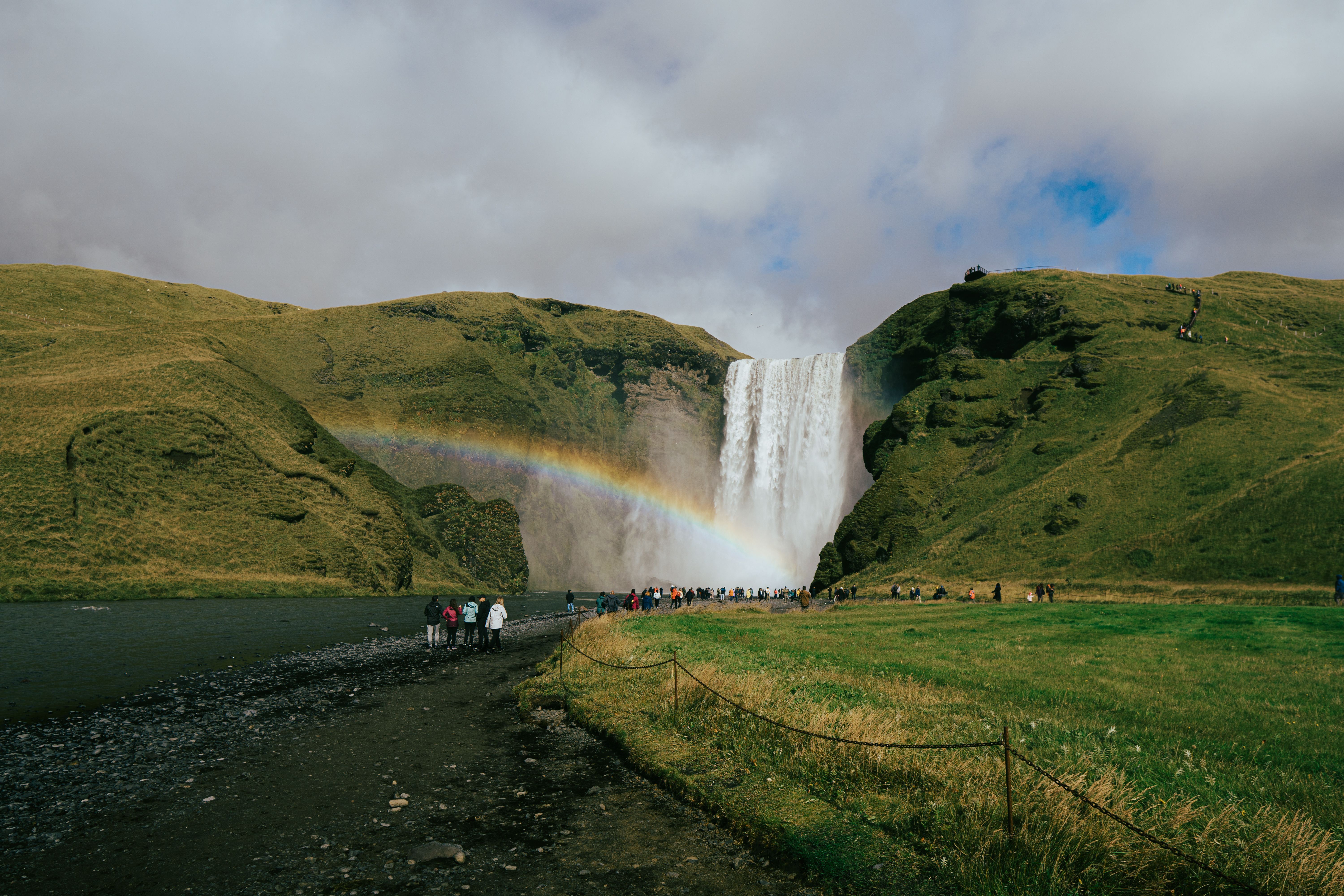 Skogafoss waterfall with a vibrant rainbow in Iceland's lush landscape.