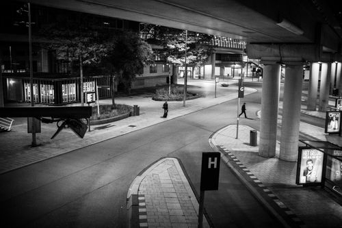 Free Monochrome urban street view at night with pedestrians, featuring stark contrasts and architectural elements. Stock Photo