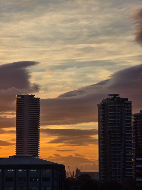 Free A vivid sunset paints the city skyline with warm hues, highlighting towering buildings. Stock Photo