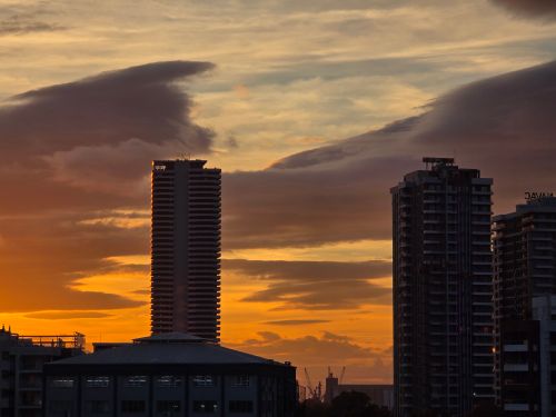 Free Silhouette of skyscrapers against a vivid orange sunset sky, creating a dramatic cityscape. Stock Photo