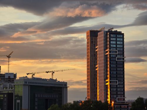 Free Modern skyscrapers and cranes at sunset with dramatic clouds in the background. Stock Photo