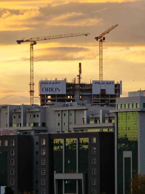 Free Modern urban development with construction cranes during a sunset. Stock Photo