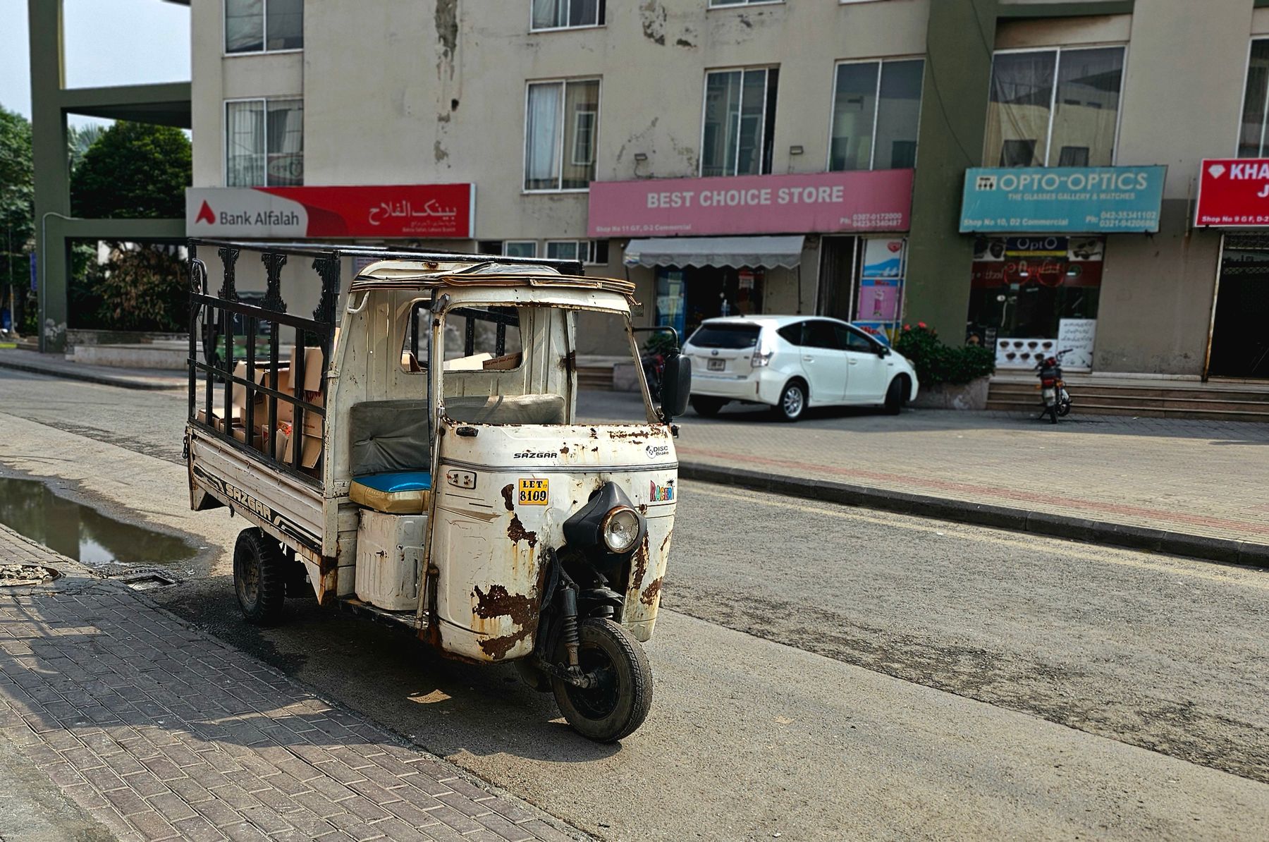 A rustic rickshaw sits on a sunny street in Lahore, Pakistan, capturing local urban life.
