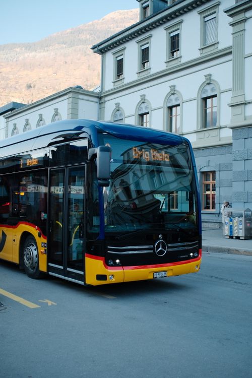 Free A modern public transport bus in Brig, Switzerland near a traditional building. Stock Photo