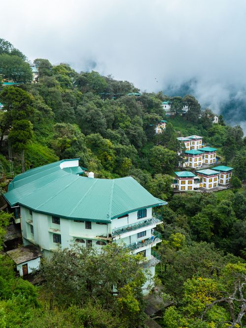 Free Captivating panoramic view of hillside homes amidst lush greenery and clouds in Mussoorie, India. Stock Photo