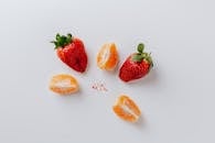 白色背景上，极简主义扁平布局中摆放着新鲜草莓和橙子片