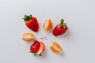 白色背景上，以极简主义扁平布局呈现新鲜草莓和柑橘片