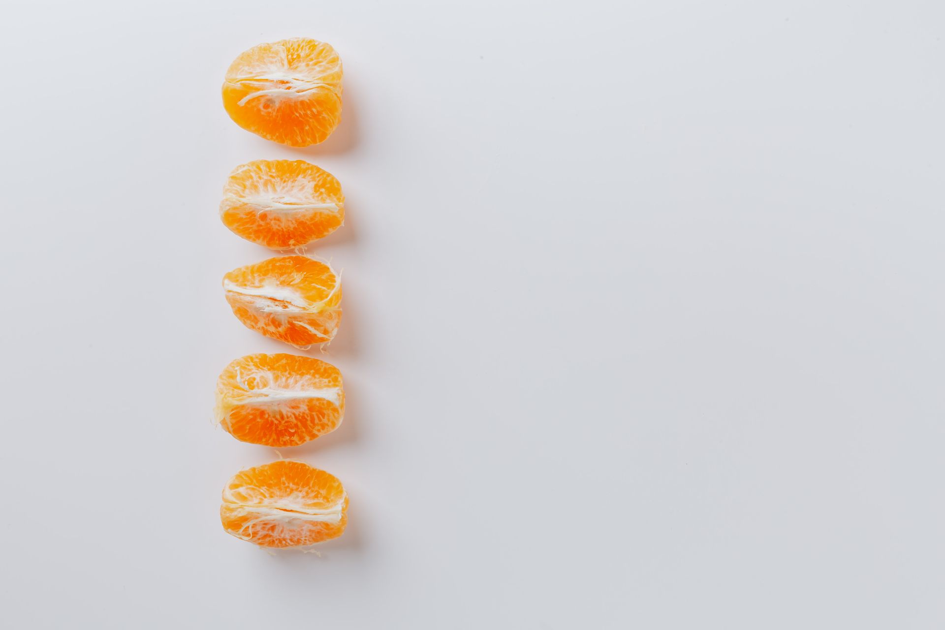 Top view of arrangement of fresh juicy ripe slices of mandarins on white table