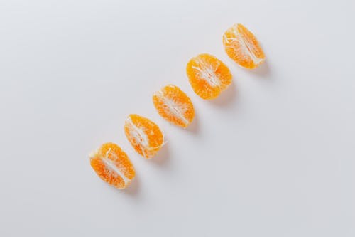 Top view of row of fresh juicy ripe slices of tangerines on white surface
