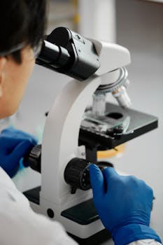 在实验室里，一名戴着手套的科学家正在操作显微镜