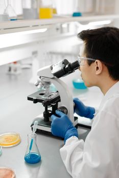 一名科学家在实验室里穿着安全装备使用显微镜，非常适合科学研究