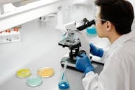 科学家在实验室里用显微镜检查样品，周围摆满了五颜六色的培养皿