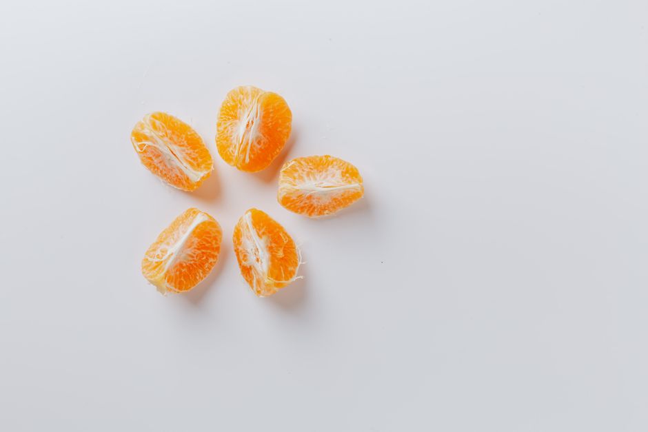 Top view of peeled fresh juicy ripe mandarin arranged on smooth white surface