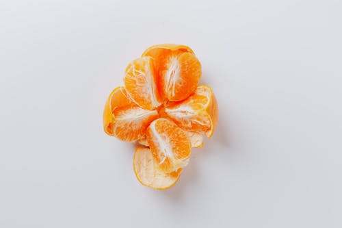 From above of fresh peeled juicy tangerine divided into five equal slices on gray background