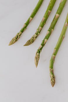 Close-up image of fresh green asparagus stalks on a white background, showcasing healthy ingredients.