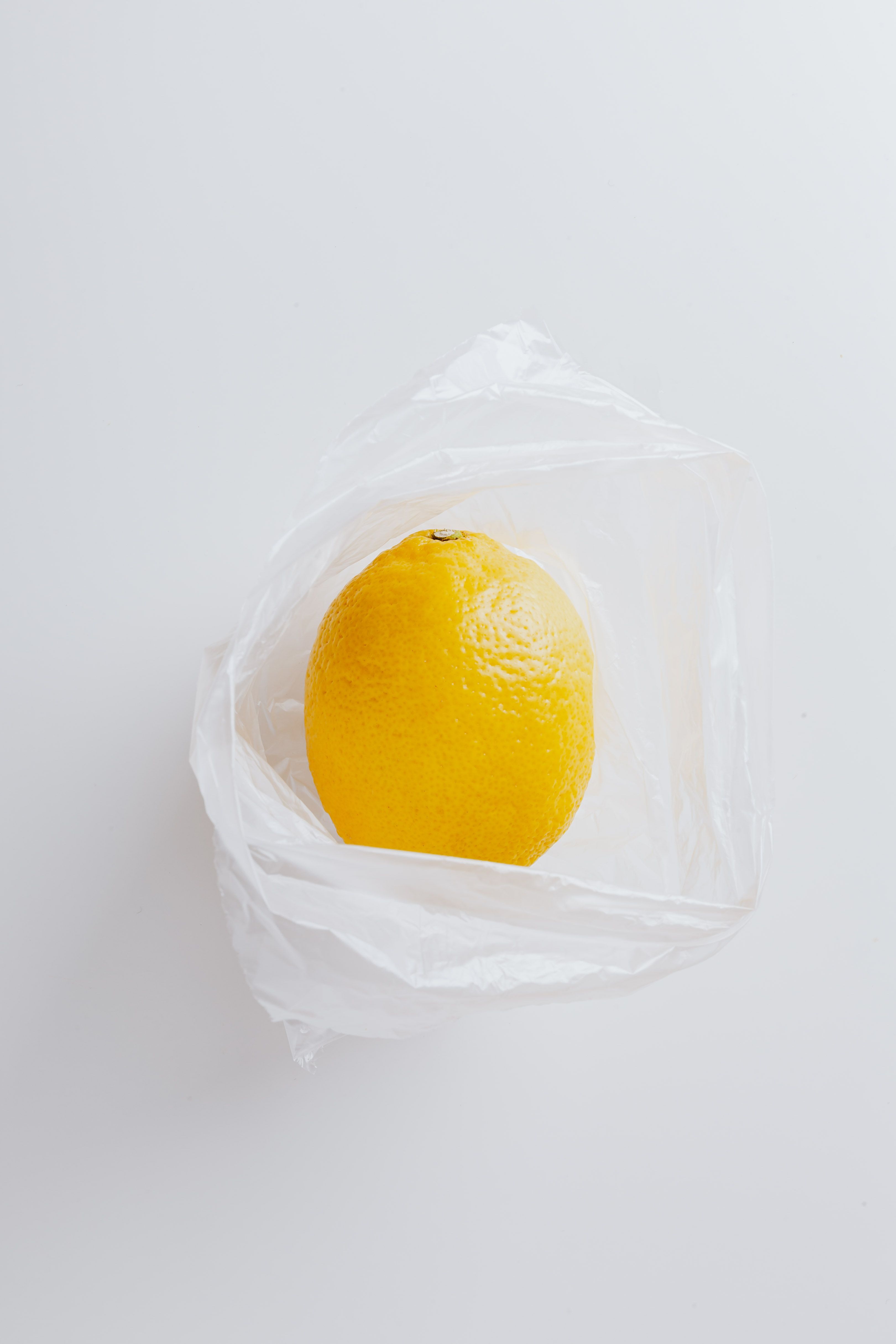 单个柠檬被装在透明的白色塑料袋里，以突出其新鲜感