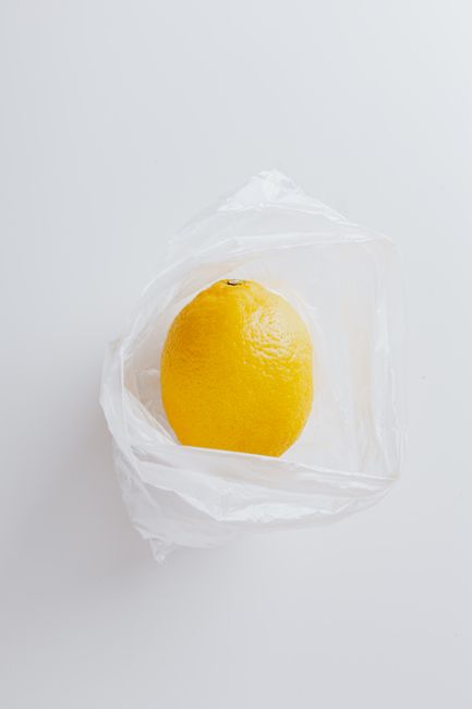 Top view of fresh ripe lemon fruit on transparent polyethylene bag on gray background