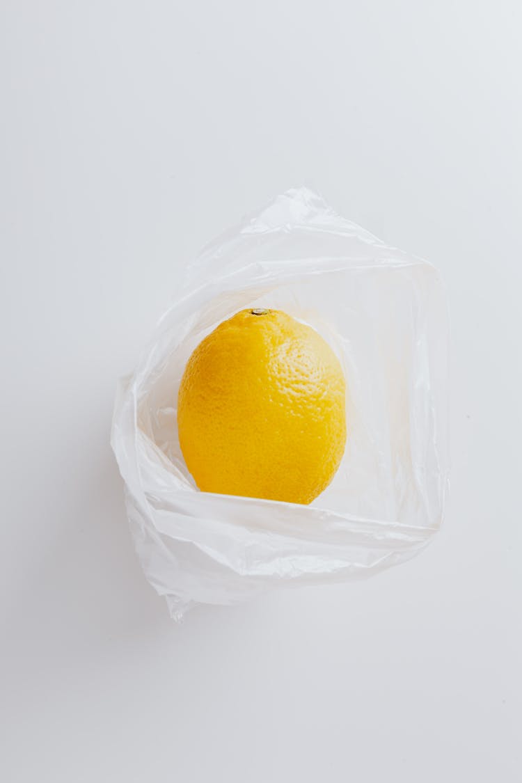 Whole Unpeeled Lemon On Polyethylene Bag On Gray Background