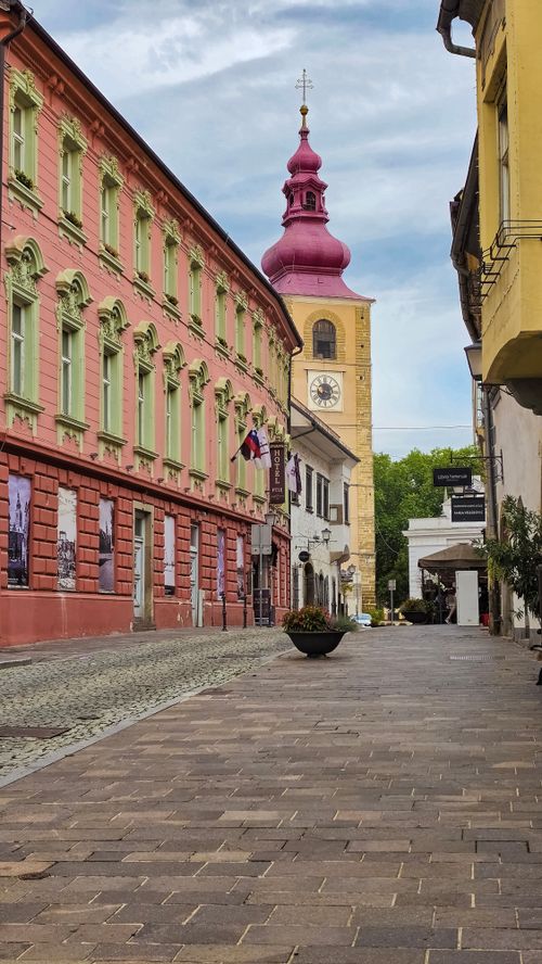 Free Scenic view of a European street featuring a historic clock tower and colorful architecture, ideal for travel enthusiasts. Stock Photo