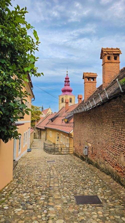 Free Cobblestone street view with a medieval church and colorful rooftops in Ptuj, Slovenia. Stock Photo