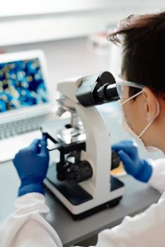 科学家在实验室里使用显微镜研究安全眼镜和手套