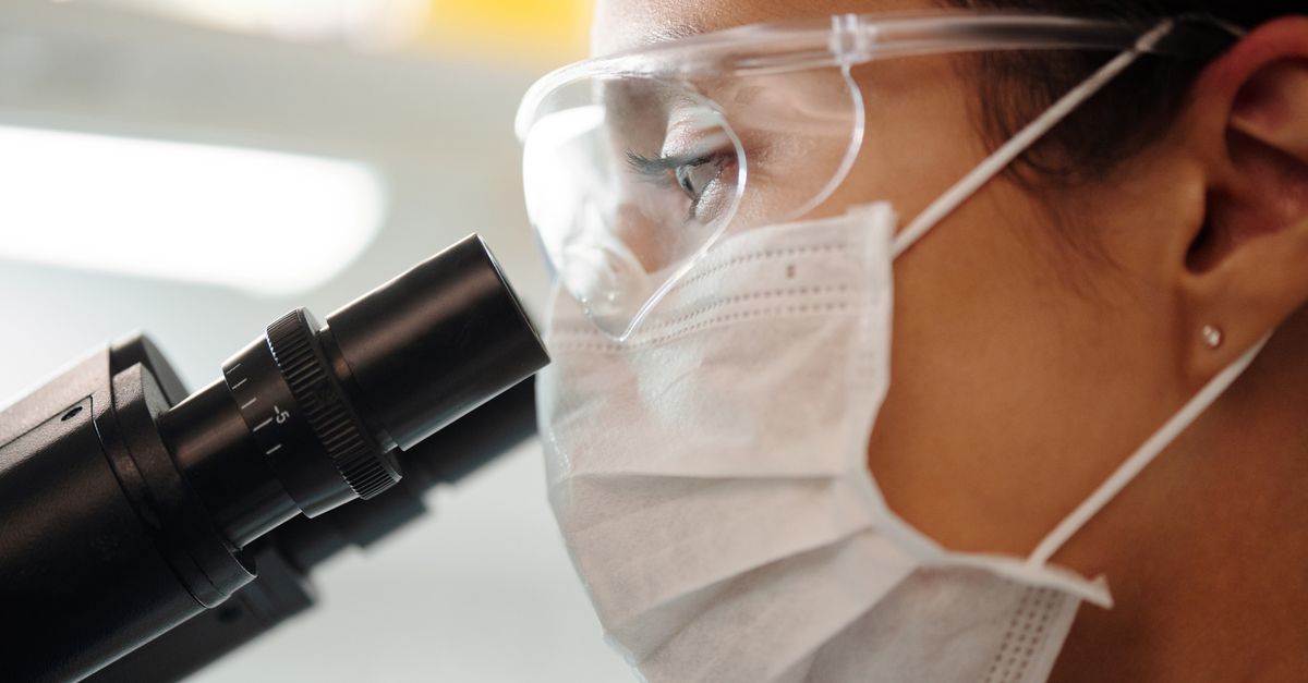Photo by Edward Jenner Close-up of a researcher with safety gear using a microscope in a lab.