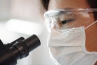 一位身穿安全装备的科学家正在室内使用显微镜进行特写拍摄