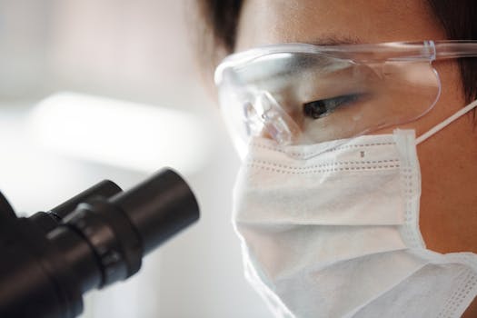 一位身穿安全装备的科学家正在室内使用显微镜进行特写拍摄