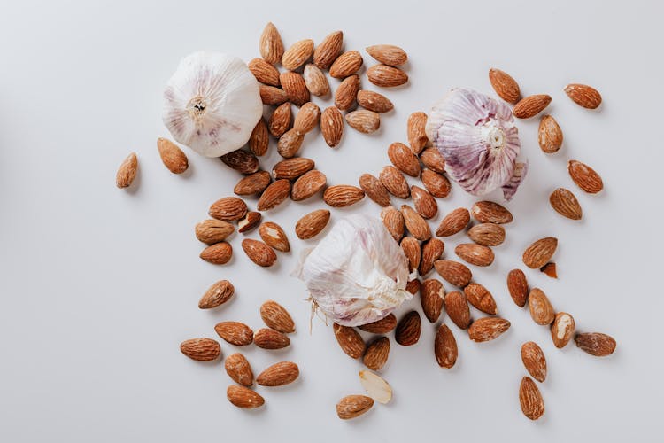 Raw Almonds And Heads Of Garlic On White Background