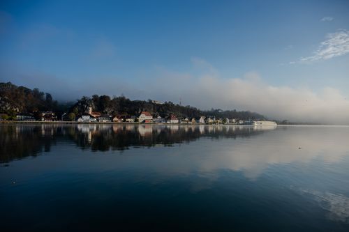 Free Serene fog-covered town along a calm river in Lower Austria captured at dawn. Stock Photo