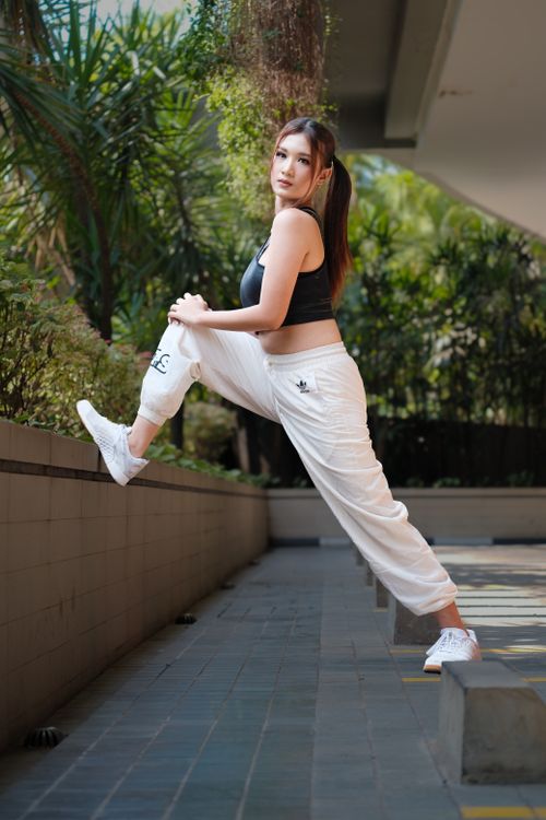 Free Fit young woman stretching outdoors in a lush garden setting in Bandung, Indonesia. Stock Photo
