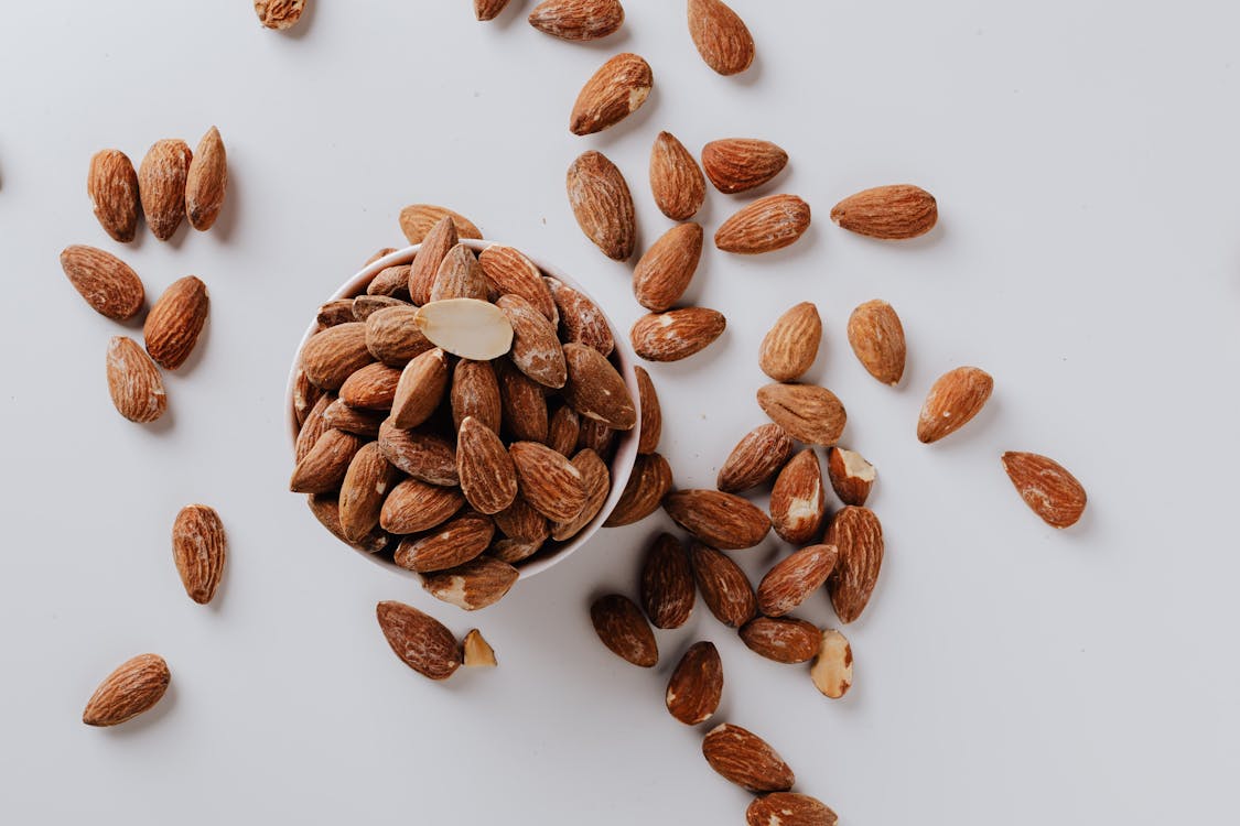 Bowl filled with raw almond nuts on white background