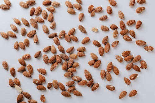 Free Top view of pile of delicious almond nuts cluttered on white table illustrating healthy food eating concept Stock Photo