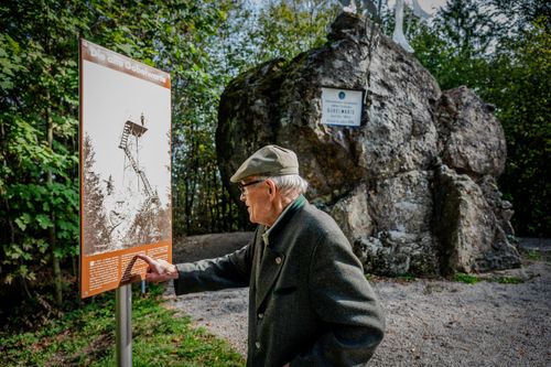 Free Senior man reading an informational board outdoors in Grein, Austria, surrounded by natural landscape. Stock Photo