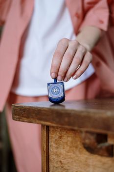 A close-up image of a hand holding a traditional blue dreidel during Hanukkah, symbolizing Jewish culture and celebration.