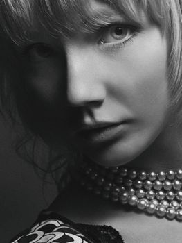 Black and white portrait of a woman wearing pearl necklace, showcasing elegance and style.