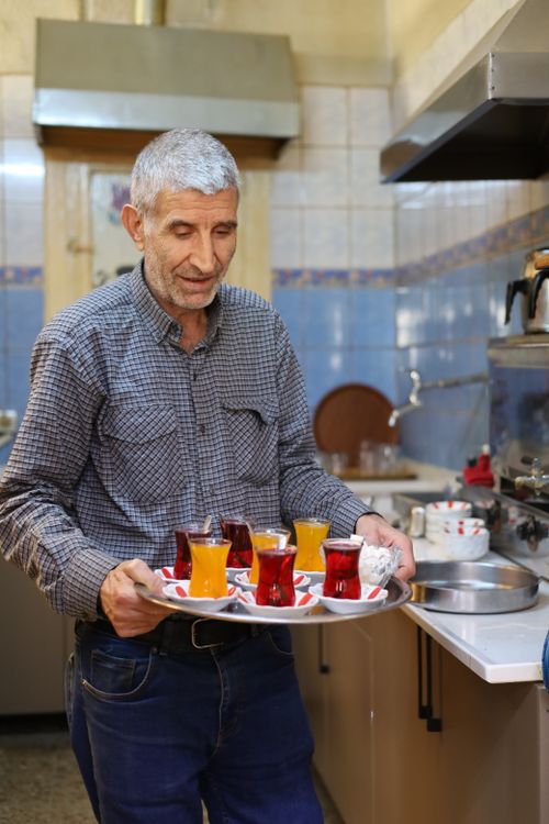 Free A senior man serving traditional Turkish tea in a cozy kitchen setting. Stock Photo