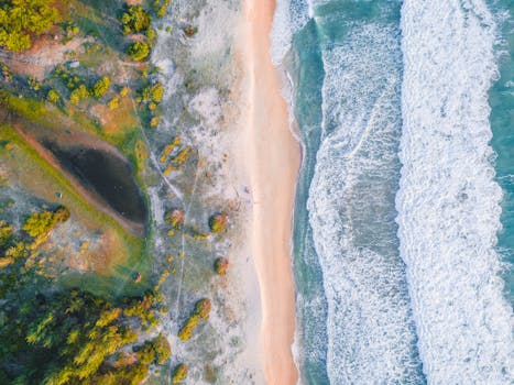 Bright and vibrant aerial view of a coastline in Aceh, Indonesia with waves crashing on a sandy beach.