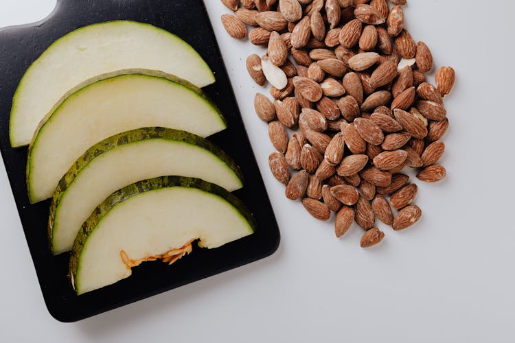 Pile Of Almonds And Chopped Melon On White Table