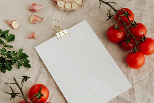 Free A rustic kitchen scene with tomatoes, garlic, parsley, and blank paper on linen. Stock Photo