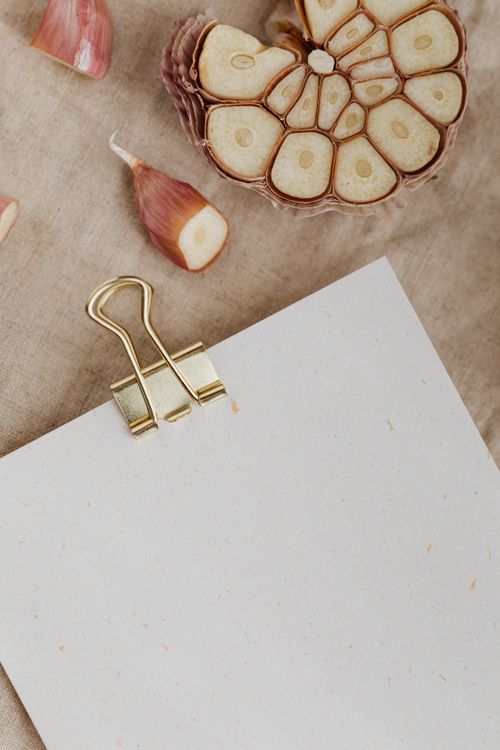 Free Aerial view of garlic cloves and sliced bulb with a clipboard on linen fabric background. Stock Photo