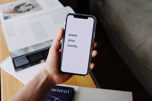 A hand holds a smartphone displaying a 'wash your hands' reminder, highlighting hygiene awareness.