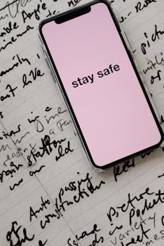 Close-up of a smartphone with 'stay safe' message on handwritten notes, emphasizing caution.