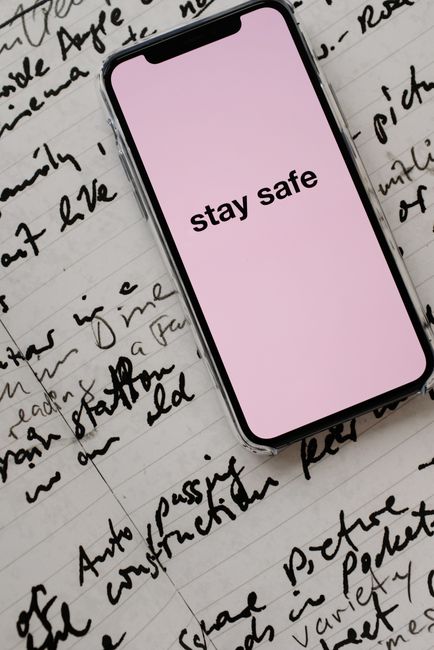 Close-up of a smartphone with 'stay safe' message on handwritten notes, emphasizing caution.